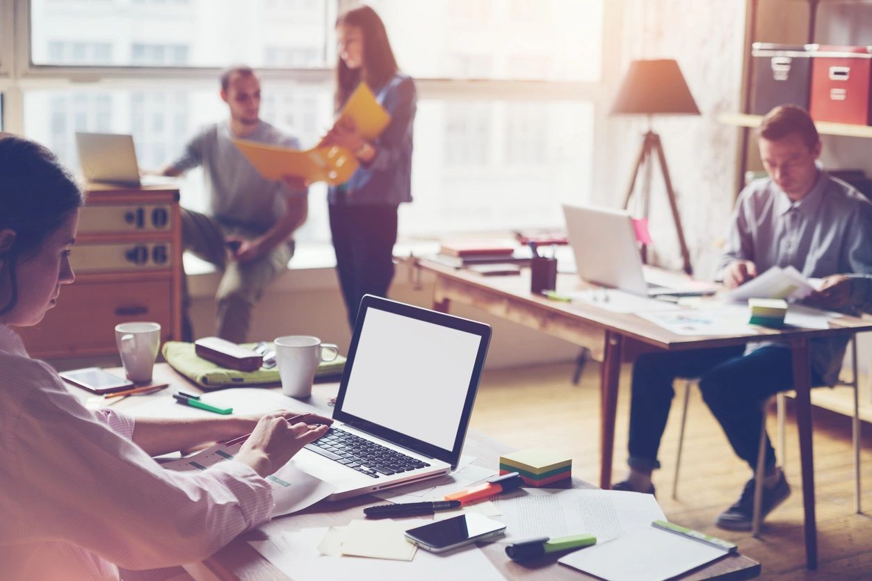 A workplace with employees and laptops.